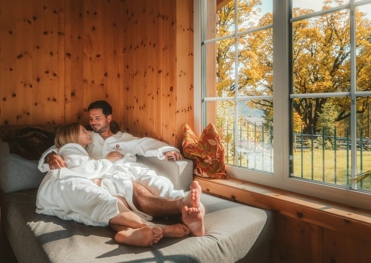 Couple relaxing in the wellness area with a view of autumnal trees at the Lindenhof