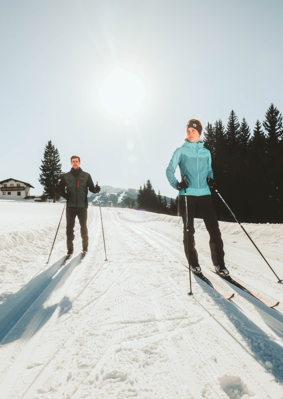  Langläufer auf einer frisch präparierten Loipe, umgeben von ruhigen Wäldern