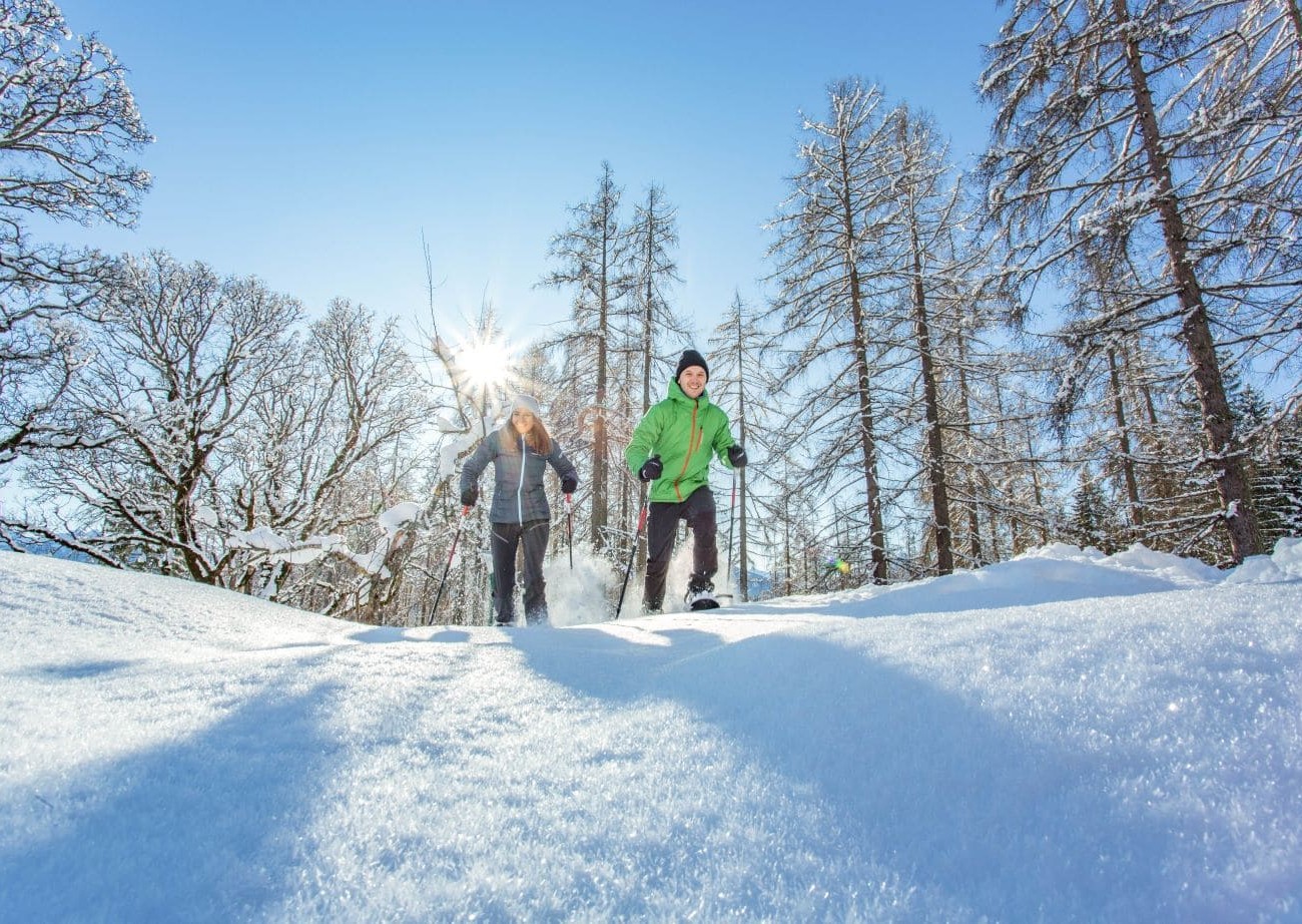 Zwei Personen beim Winterwandern im Schnee vor einer Bergkulisse
