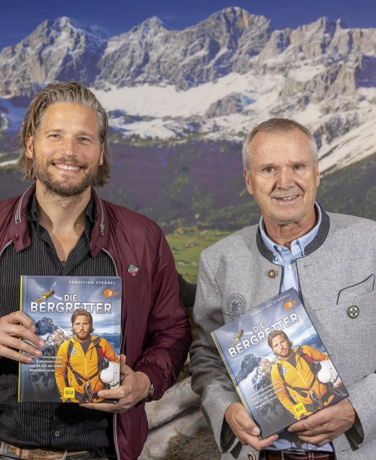 Sebastian Ströbel und Heribert Eisl präsentieren das Buch Die Bergretter mit Geschichten rund um Dreharbeiten in Ramsau am Dachstein