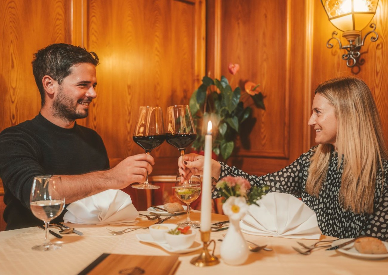 Couple enjoying a romantic candlelit dinner in the cozy restaurant of Hotel Lindenhof in Ramsau am Dachstein