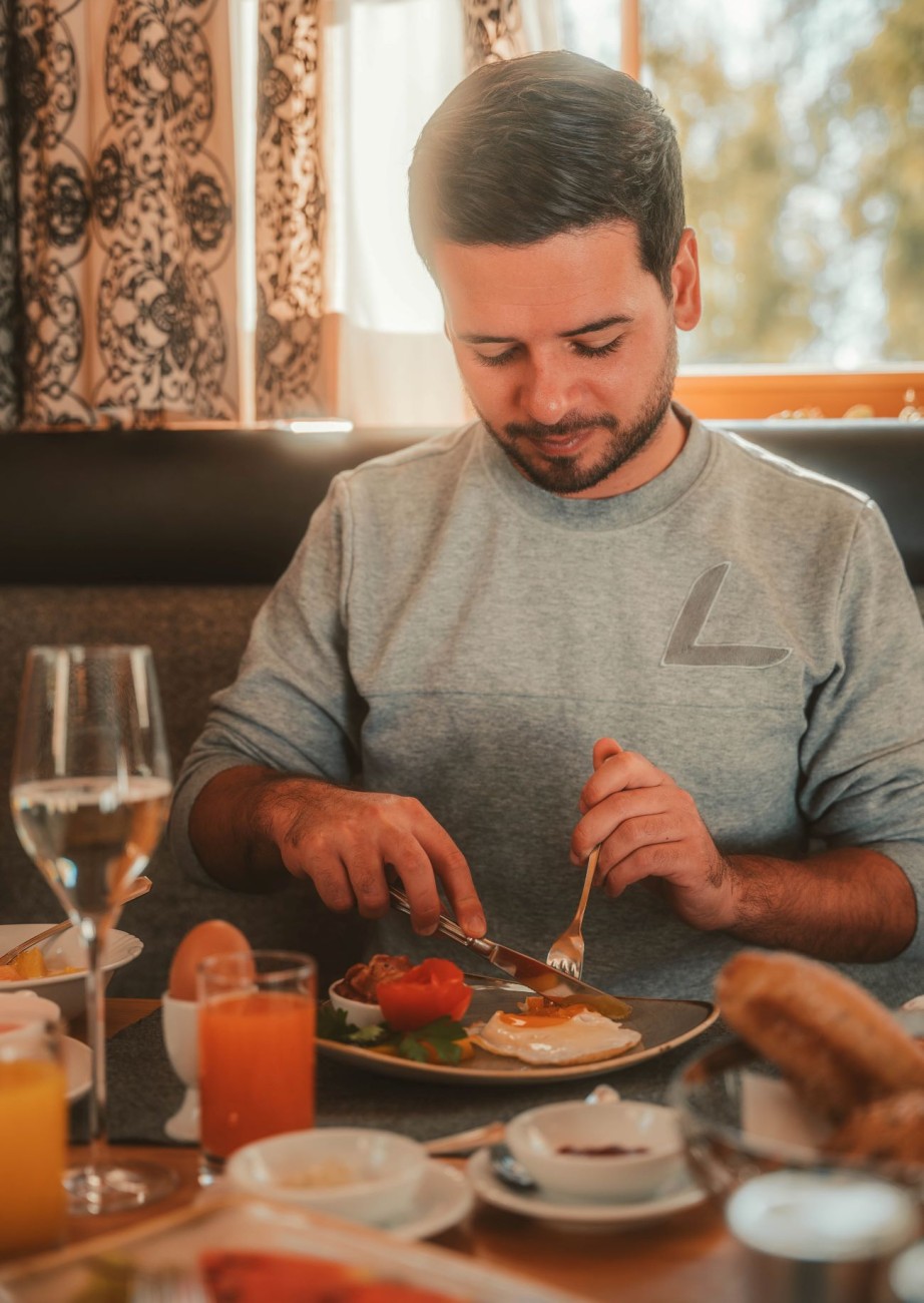 Ein Gast genießt ein reichhaltiges Frühstück im gemütlichen Restaurant des Hotel Lindenhof in Ramsau am Dachstein