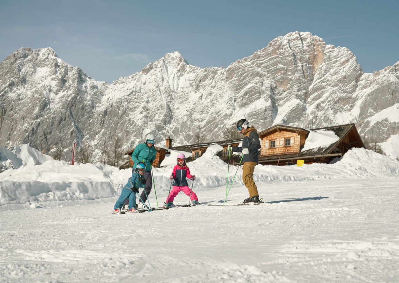 Family enjoys skiing in front of a breathtaking mountain backdrop, children learn while having fun on the slopes