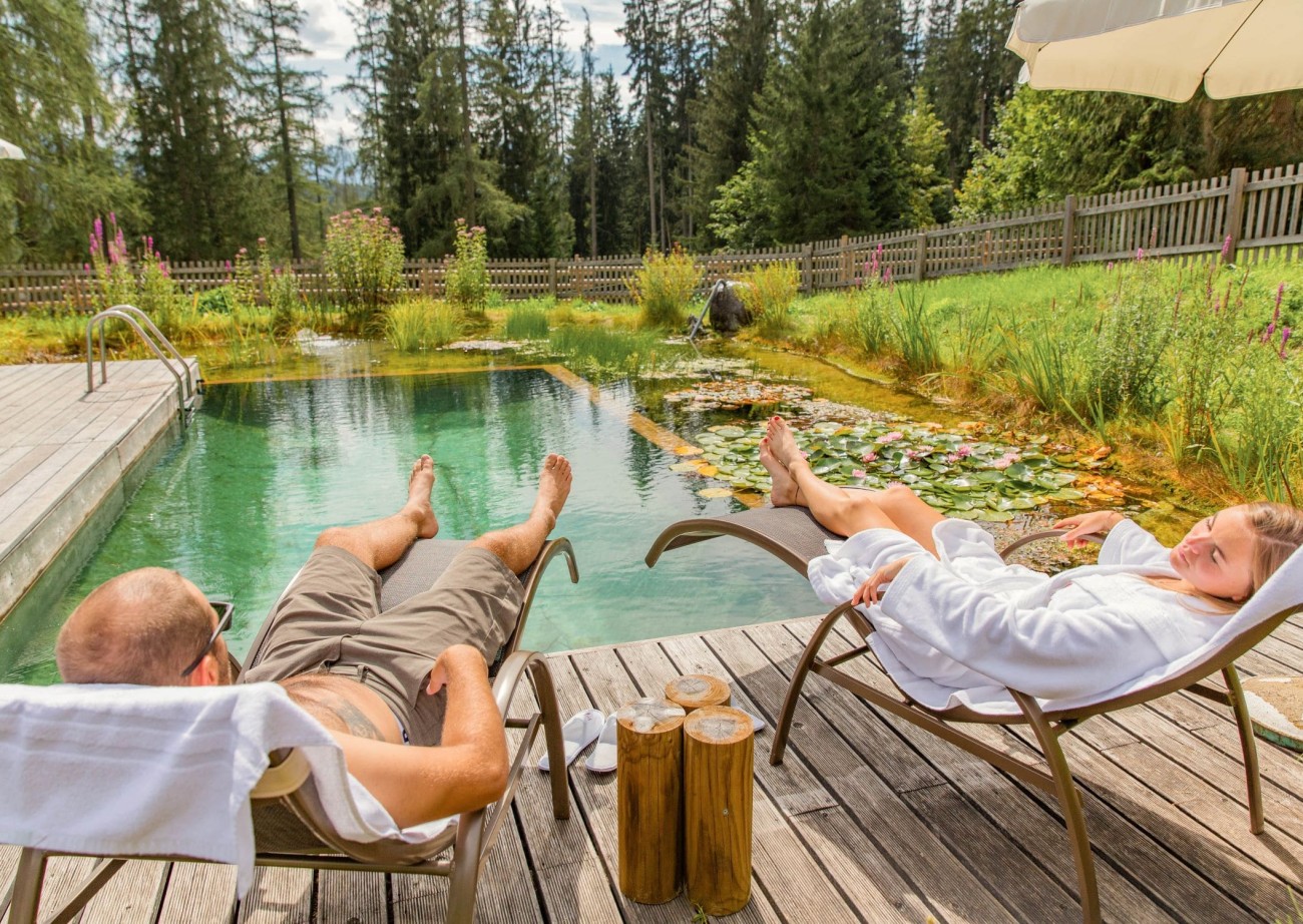 Sunbathing next to a natural swimming pond, surrounded by a tranquil forest landscape