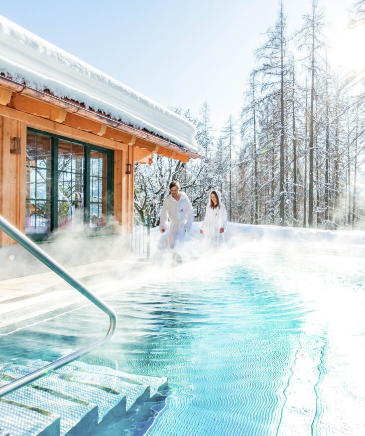 Couple relaxing in a steamy heated outdoor pool in winter