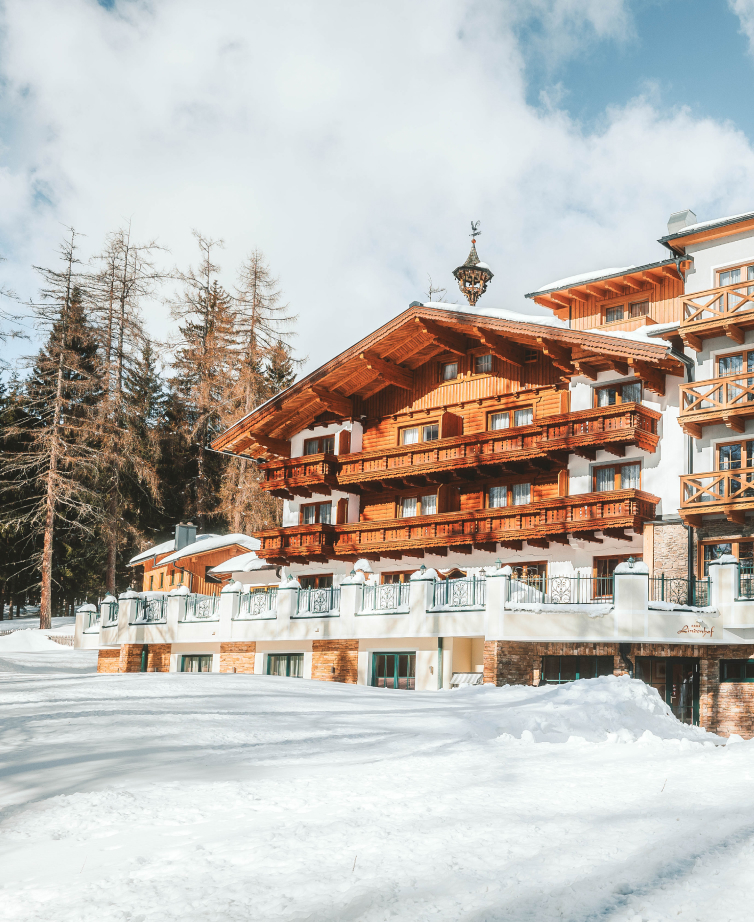 Winter view of the Hotel Lindenhof with snow-covered mountains in the background.