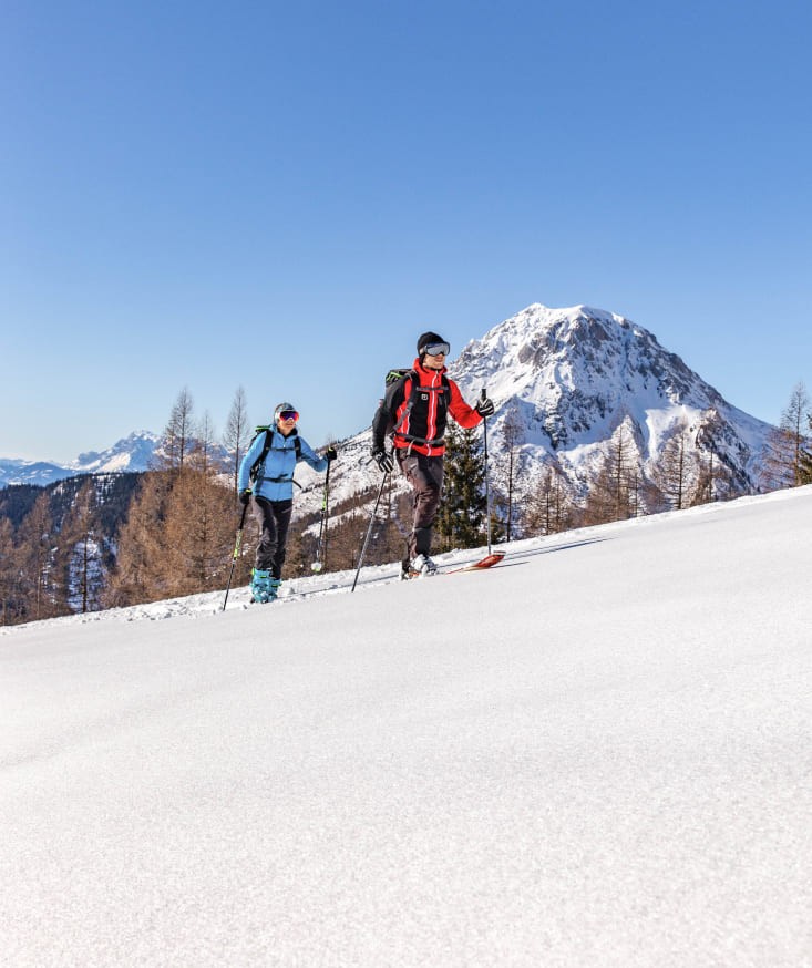 Ski tourers climb a snowy slope in Ramsau